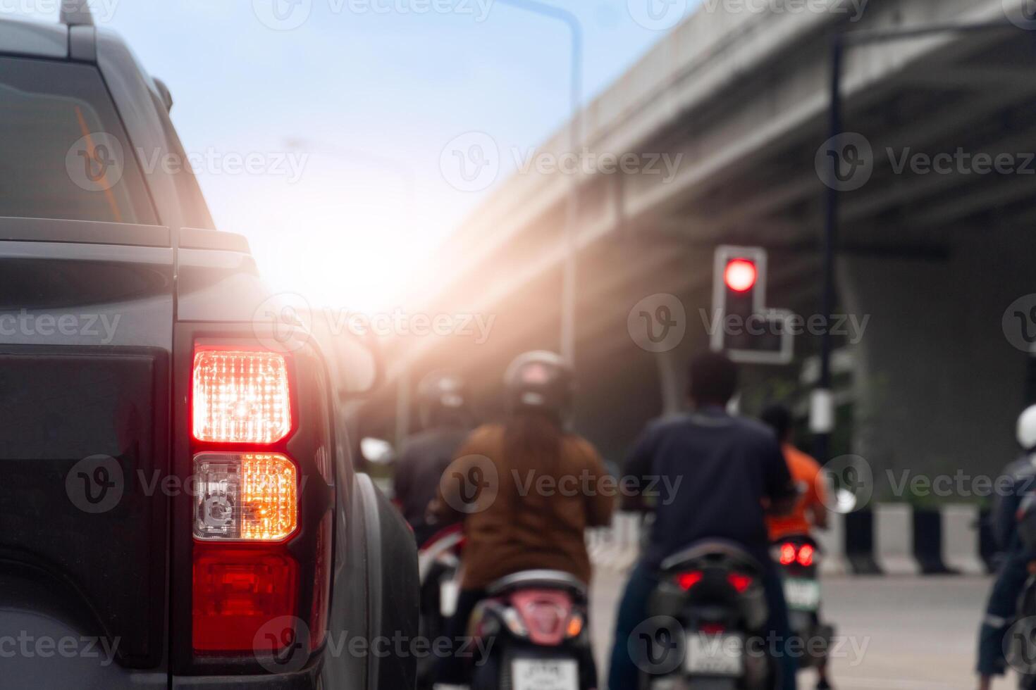Rear side view of pickup car black color with turn signal. Motorcycle with rider stops at traffic light. Intersection under the concrete overpass. Sight of traffic in Thailand. photo