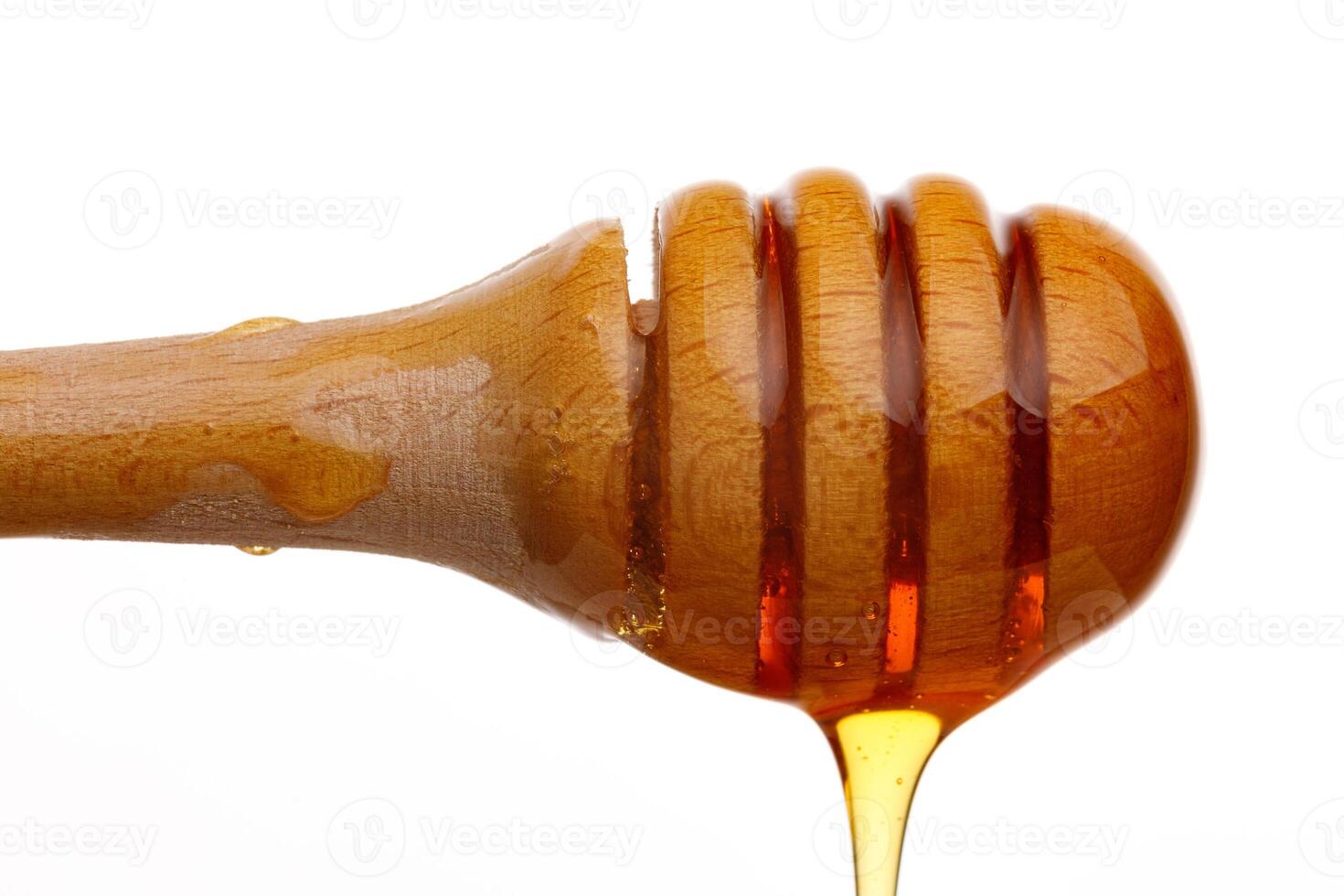 Honey dripping from a wooden dipper on a white background isolate photo