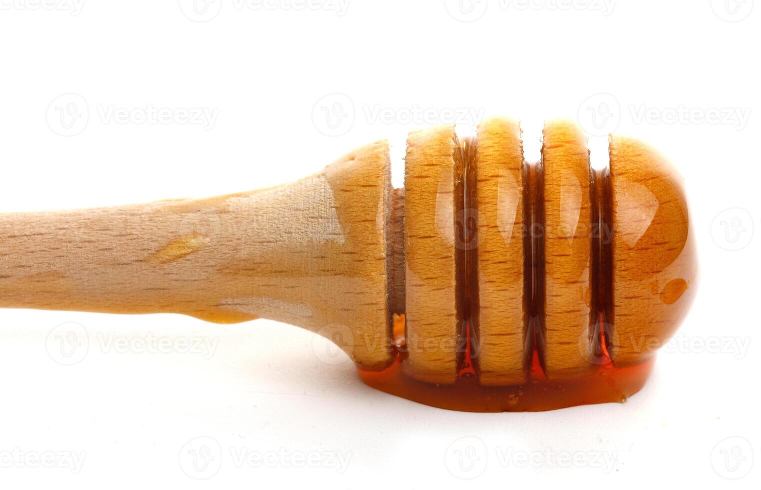 Honey dripping from a wooden dipper on a white background isolate photo