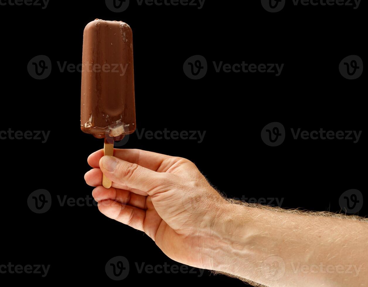 Chocolate ice cream on a stick in hand photo