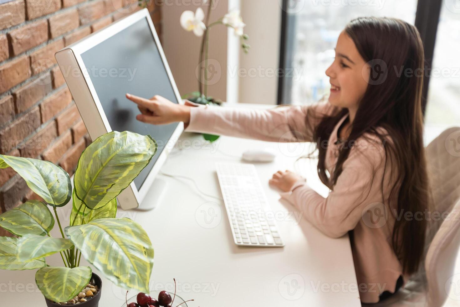 Home schooling. A girl is sitting at a table with a laptop during an online chat of a school lesson with a teacher and class. Concept of distance education. Self-isolation in quarantine. photo