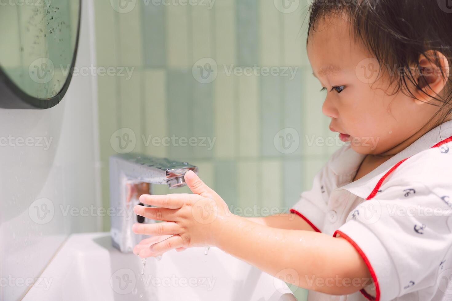 A sweet toddler diligently washes their hands in the sink, demonstrating good hygiene habits in a simple yet powerful image. Little Hands, Big Hygiene. Child boy aged 1-2 years old. photo