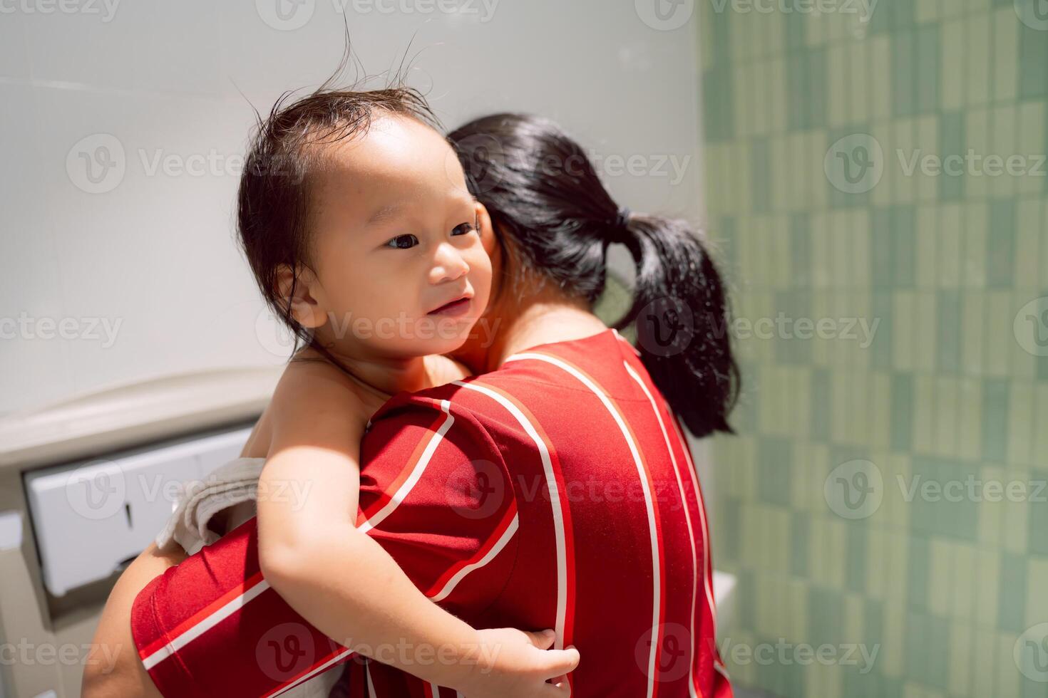 Portrait of Little boy getting dressed in family bathroom, public restroom, mother hugging toddler to wipe his diaper. Smiling child with cute expression and innocent eyes. Childcare concept. photo