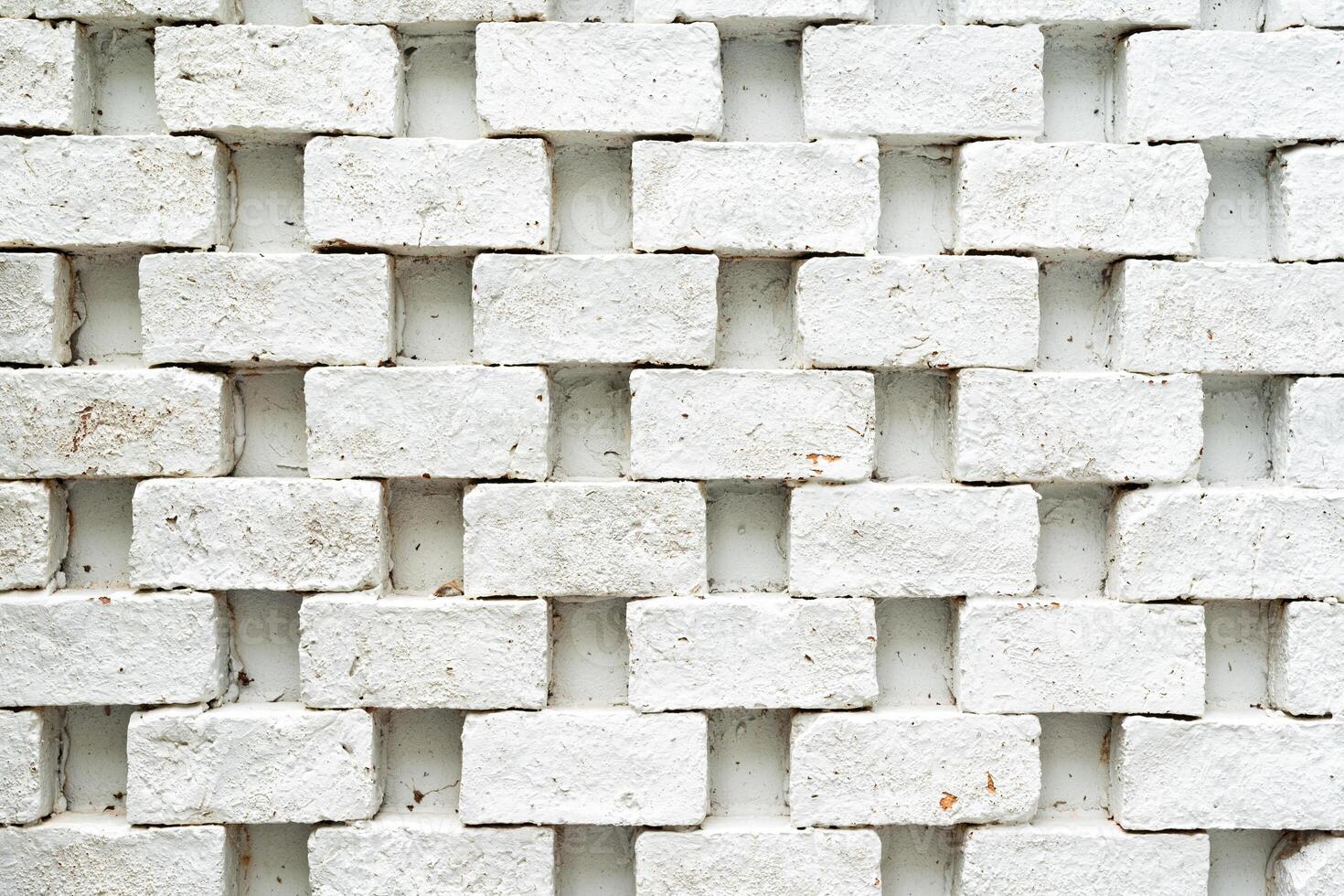 A white brick wall. The bricks are arranged in a regular pattern, with each row offset from the one above and below it. photo