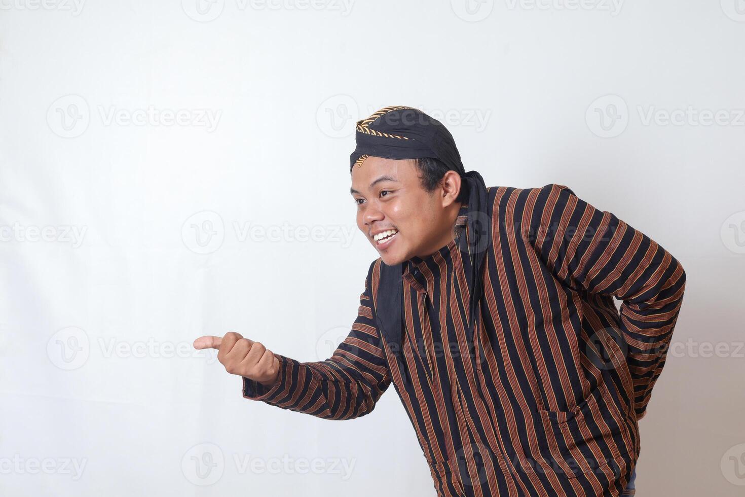 Portrait of friendly Asian man in javanese cloth with blangkon hat inviting someone to come in the most polite manner. Isolated image on white background photo