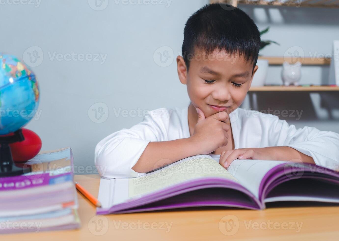 The child smile thinking sitting at table with book. Education, Childhood, People, Homework and school concept. Student learning study reading book while sitting at home. photo