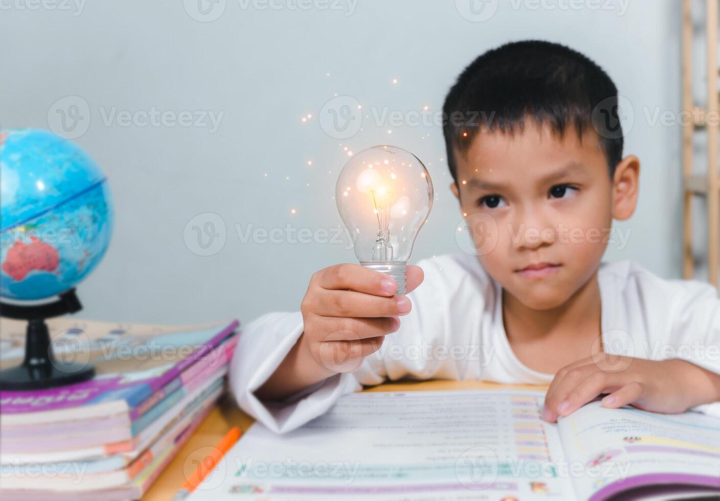 Education concept, Smart kid against green blackboard, Boy holding a bright light bulb to represent new creativity, Idea and creativity concept, Copy space for your text. photo