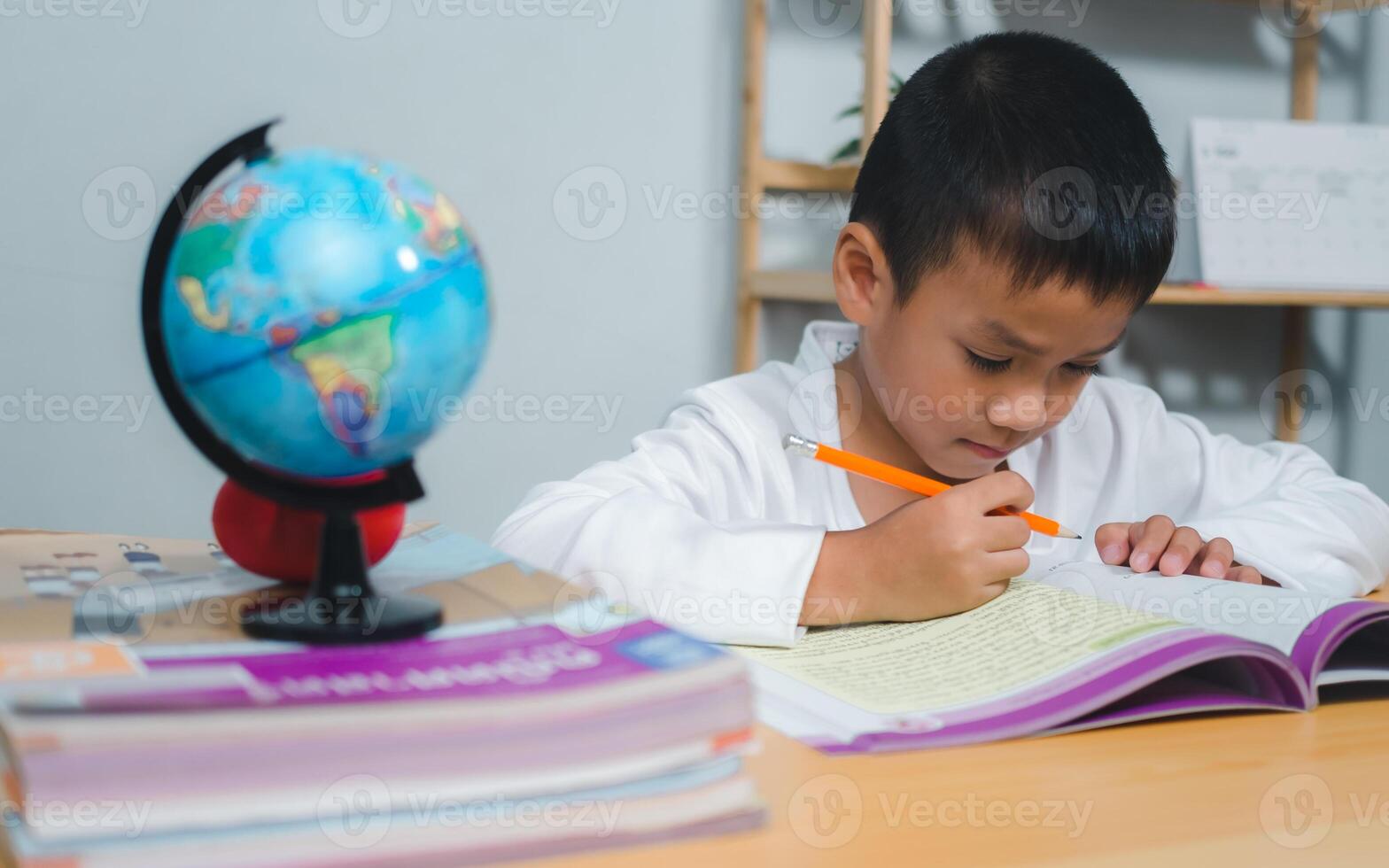 Education, Childhood, People, Homework and school concept. Student boy with book writing to notebook at home, Student learning study reading book while sitting at home. photo