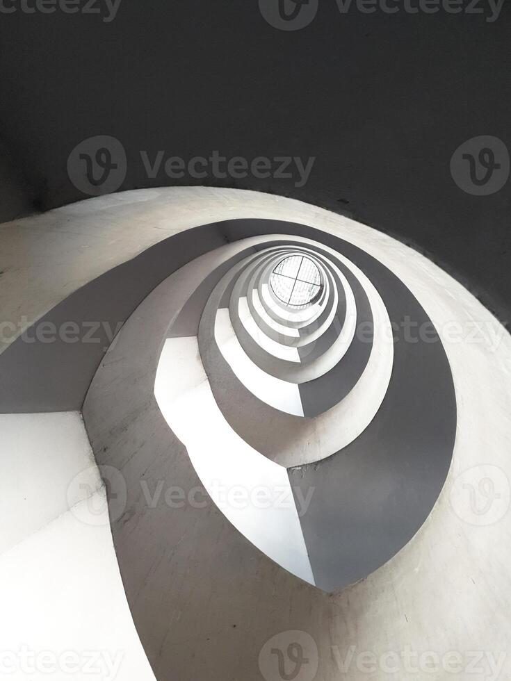 Cement spiral staircase see from the bottom up in an old building from the 90s. The light and shadow are clear and there is a perfect difference feeling of weightlessness with beautiful architecture photo