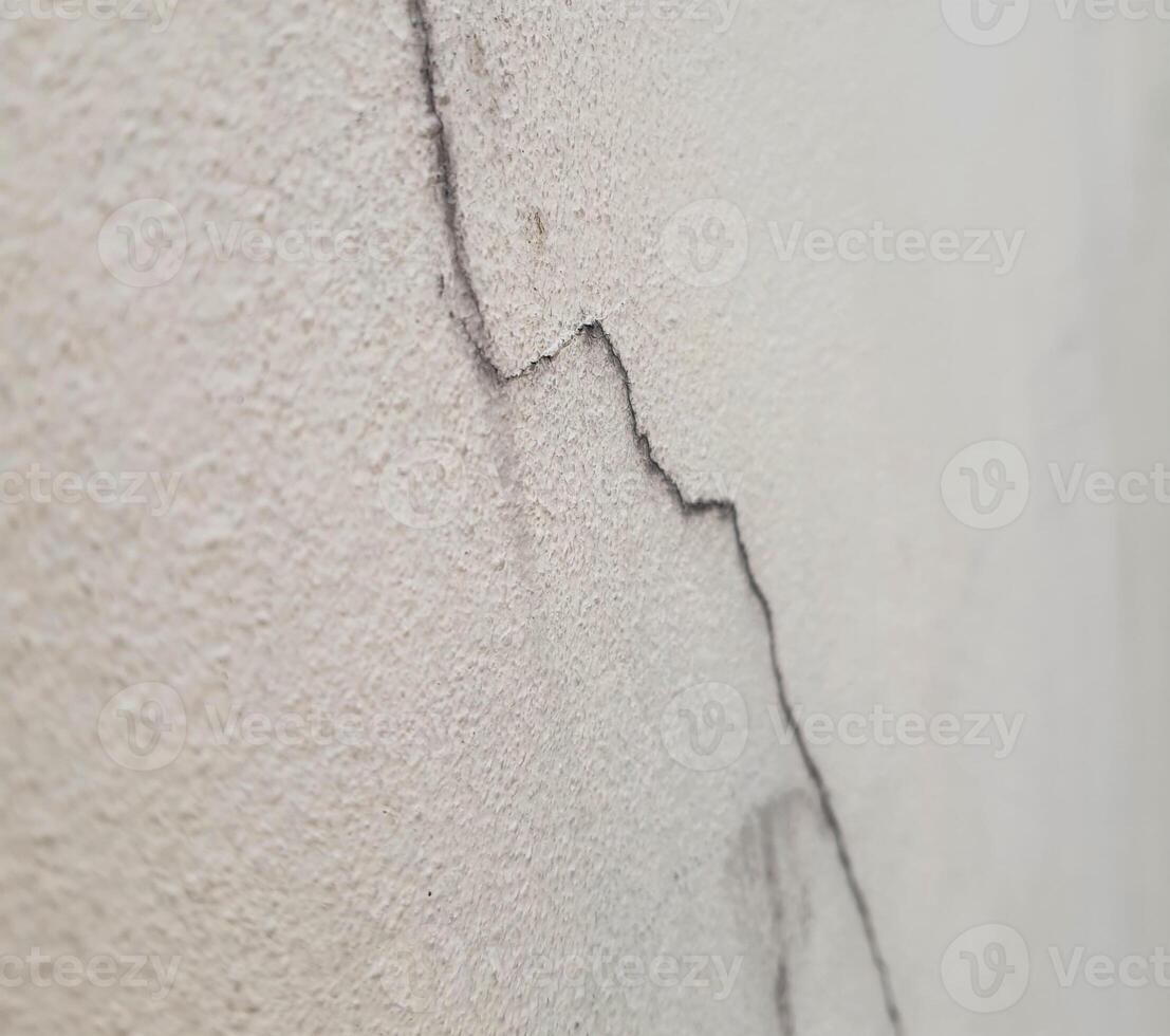 The cracks on the cream-colored concrete wall are long lines like mountains. The surface of the concrete is clearly visible, giving an unusual feeling. photo