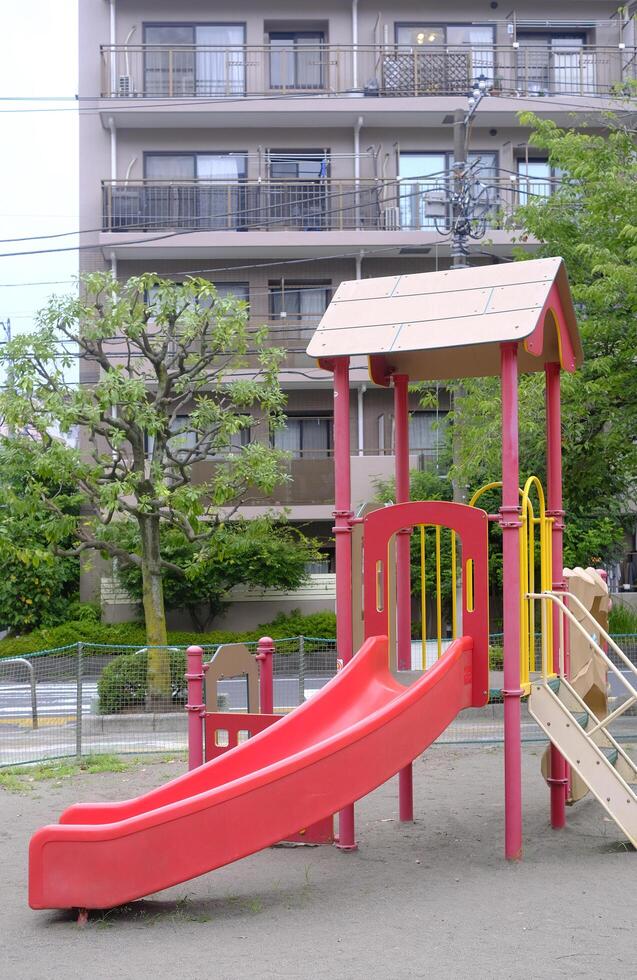 Red joyful slide for child and kids in Japanese residential playground photo