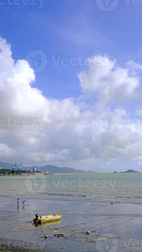 Vertical natural landscape background, fishing boat, ocean, beach and white clouds photo
