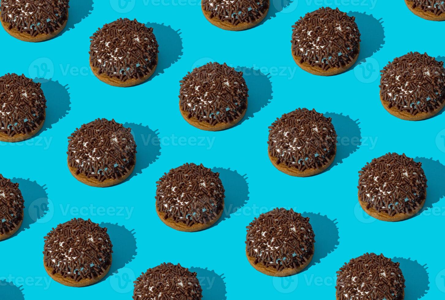 Creative trendy pattern made of sweet cookies on bright blue background. Minimal tasty biscuits concept. Yummy sweet food pattern background idea. Cookies aesthetic. photo