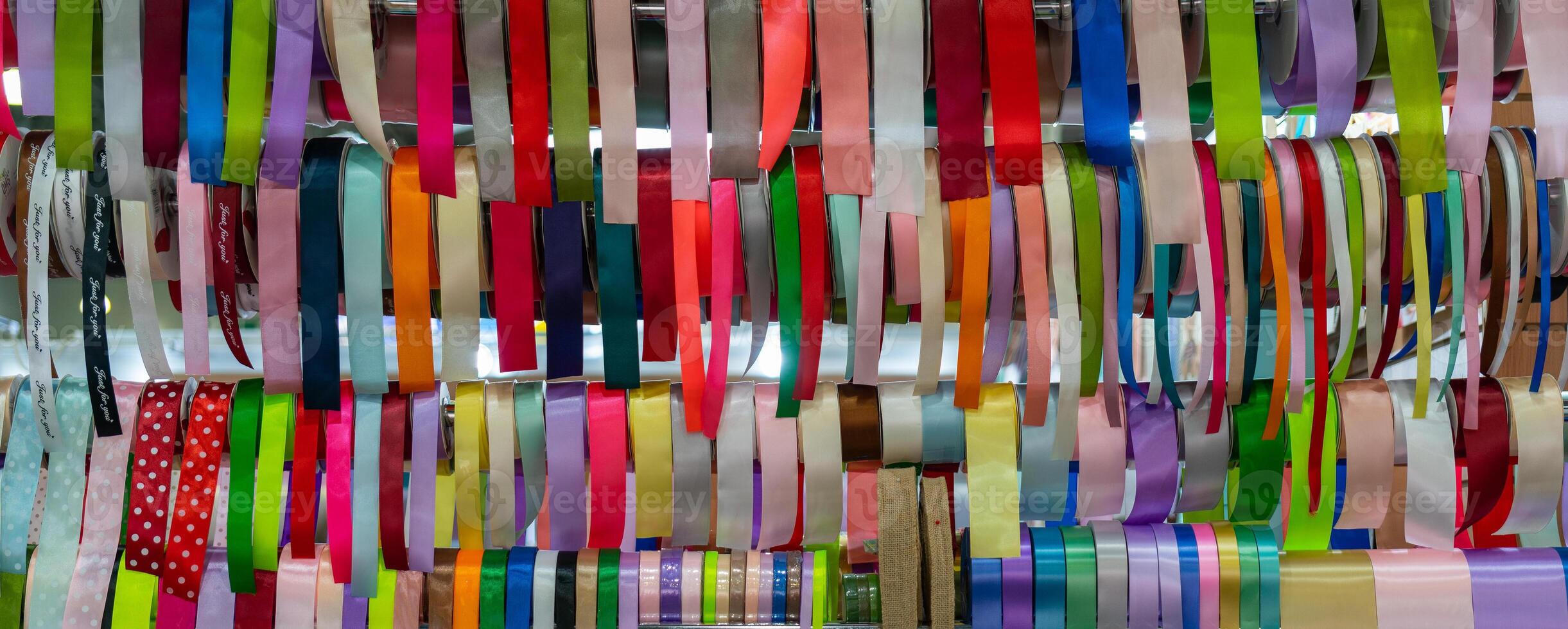 Rolls of multicolored silk ribbons in a shop window. Accessories for packing and decorating gifts. photo