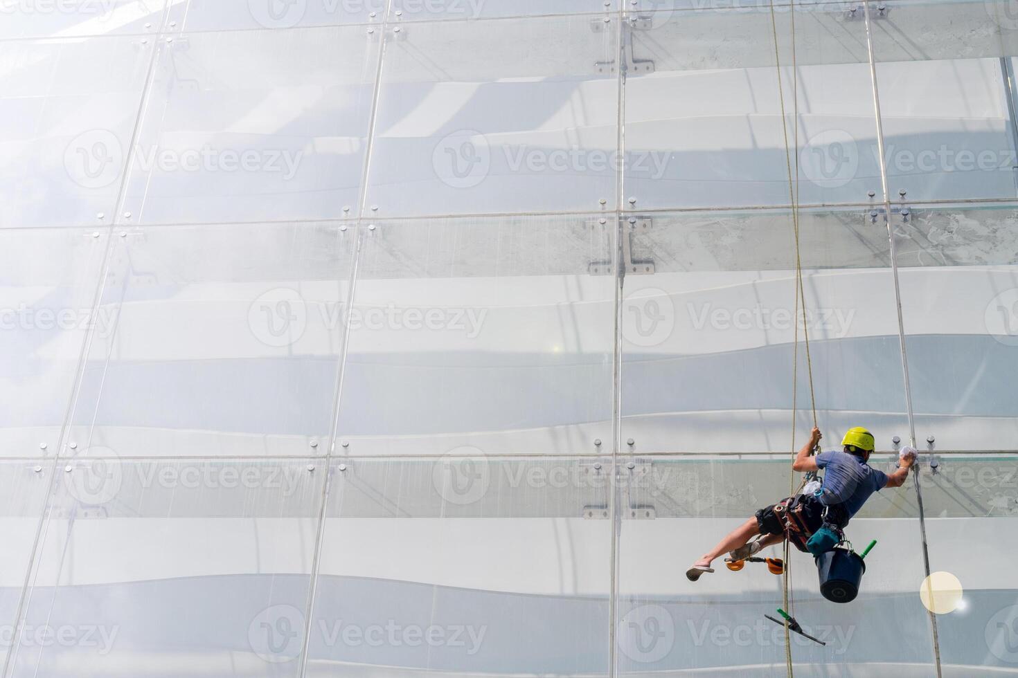 Window washer works on the wall of a glass building. photo