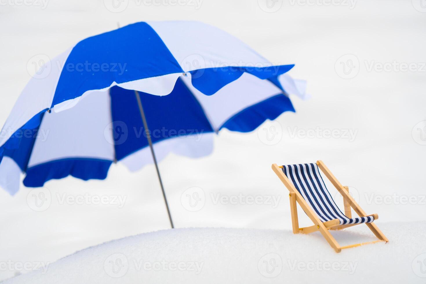 A blue, wooden, striped wooden beach chair in the snow. photo