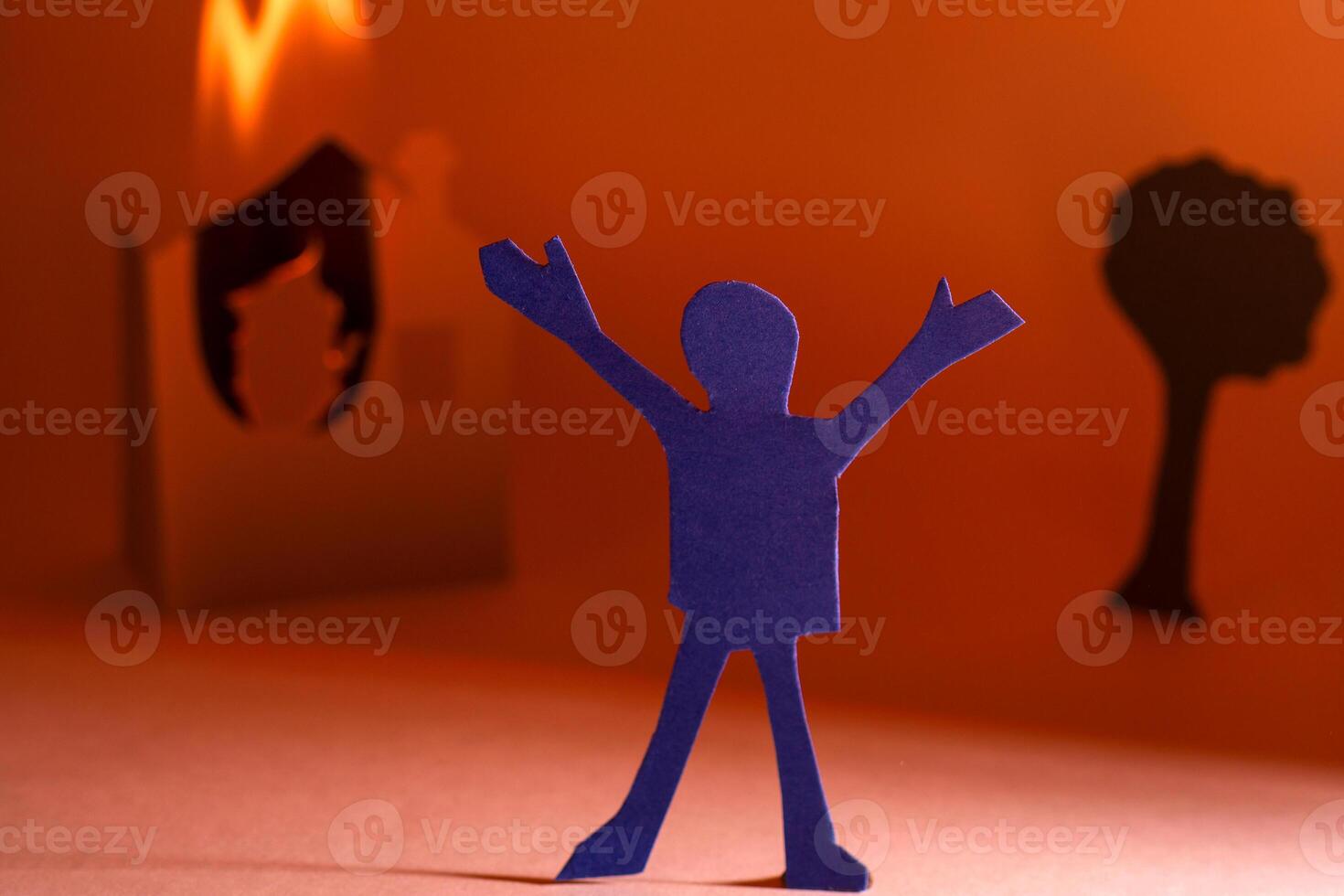 Cut from a paper person against a burning house. photo