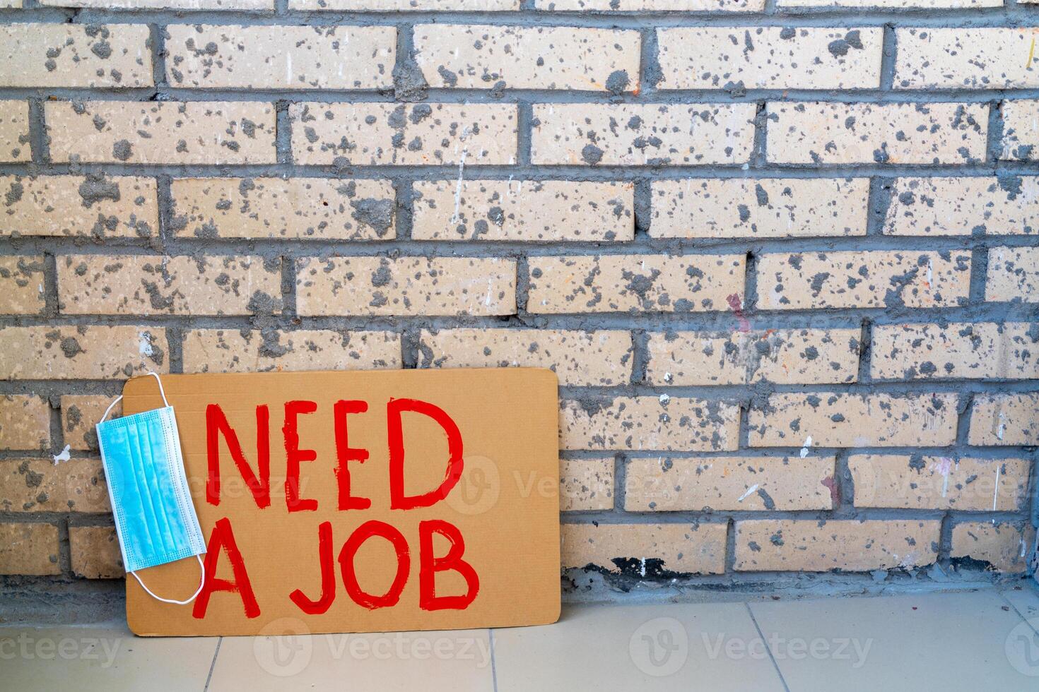Poster looking for work near brick wall.Medical mask is hanging on poster. Unemployment during crisis. photo