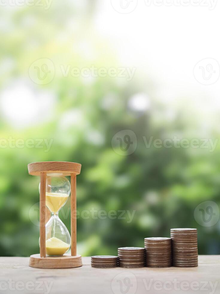 Hourglass and stack of coins. The concept of saving money for manage time to success business photo