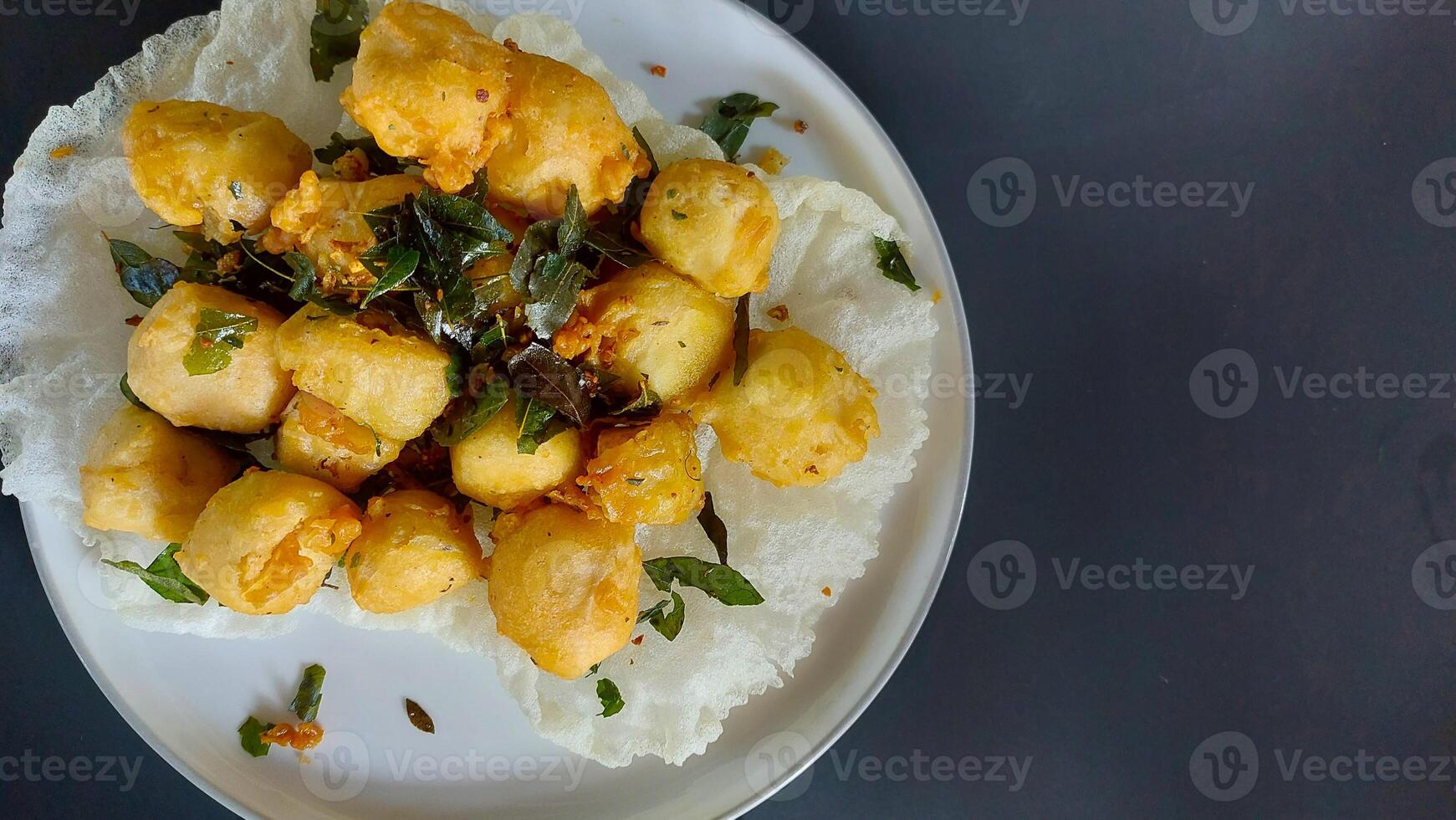 Tahu goreng cripsy, or crispy fried tofu, is one type of snack in Indonesia. With orange leaf on a white plate photo