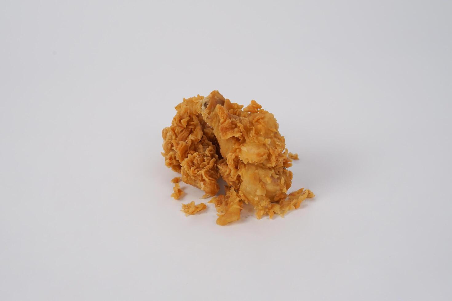 Golden brown fried chicken on white background. Fried chicken isolated over white. Fried chicken isolated on white background. Crispy fried chicken pieces in mid-air with crumbs scattering isolated photo