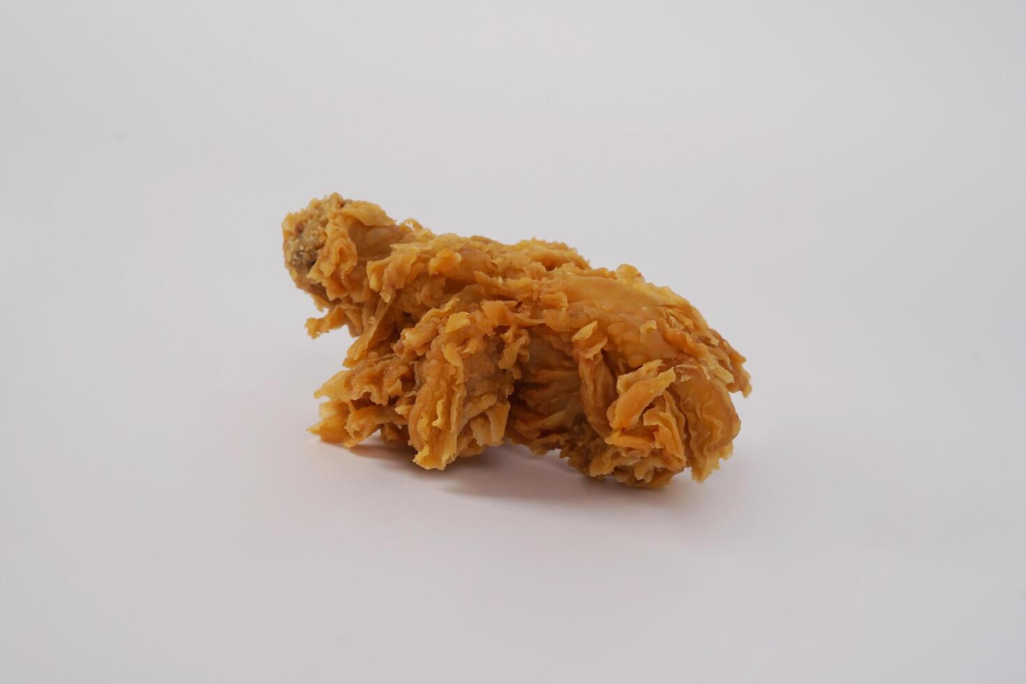Golden brown fried chicken on white background. Fried chicken isolated over white. Fried chicken isolated on white background. Crispy fried chicken pieces in mid-air with crumbs scattering isolated photo