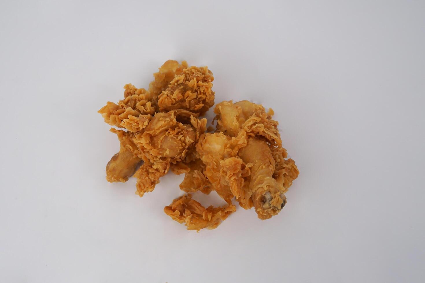 Golden brown fried chicken on white background. Fried chicken isolated over white. Fried chicken isolated on white background. Crispy fried chicken pieces in mid-air with crumbs scattering isolated photo