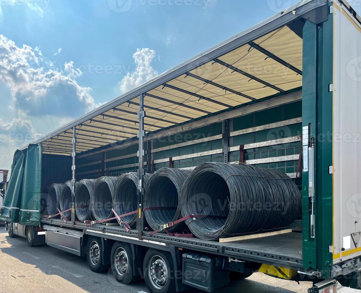 An open semi-trailer truck carrying metal wire. Industrial logistics and transportation of goods photo