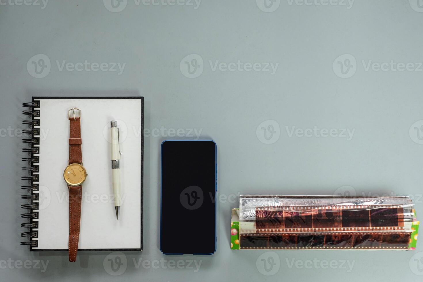 Notebook with ancient watch, pen, smartphone and retro film on background photo