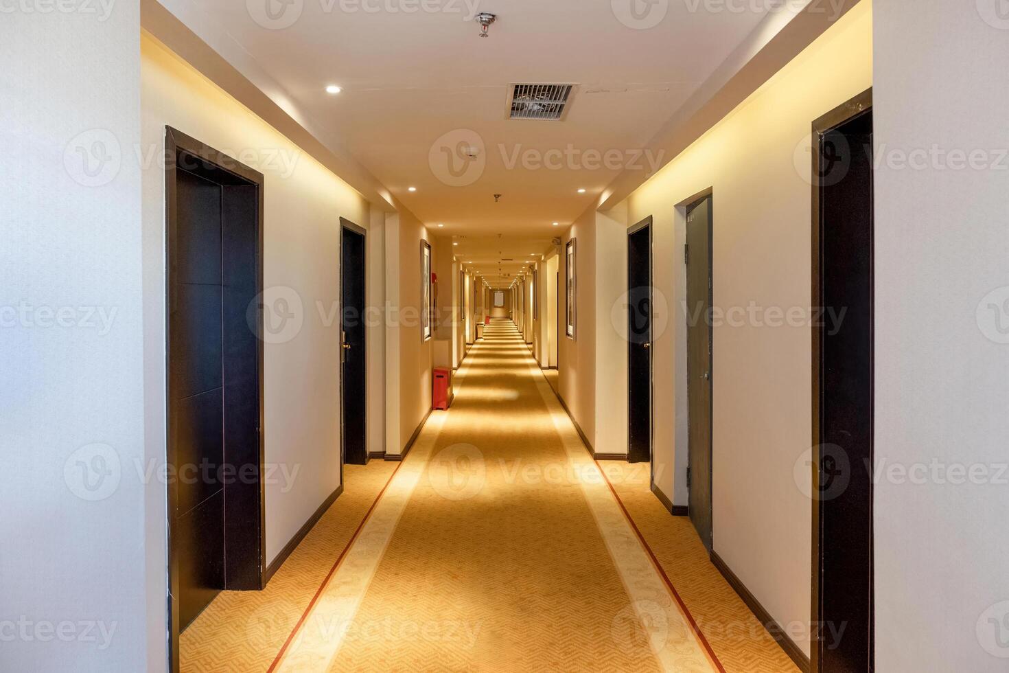 Hallway straight with the door and golden lighting illuminated in the hotel photo