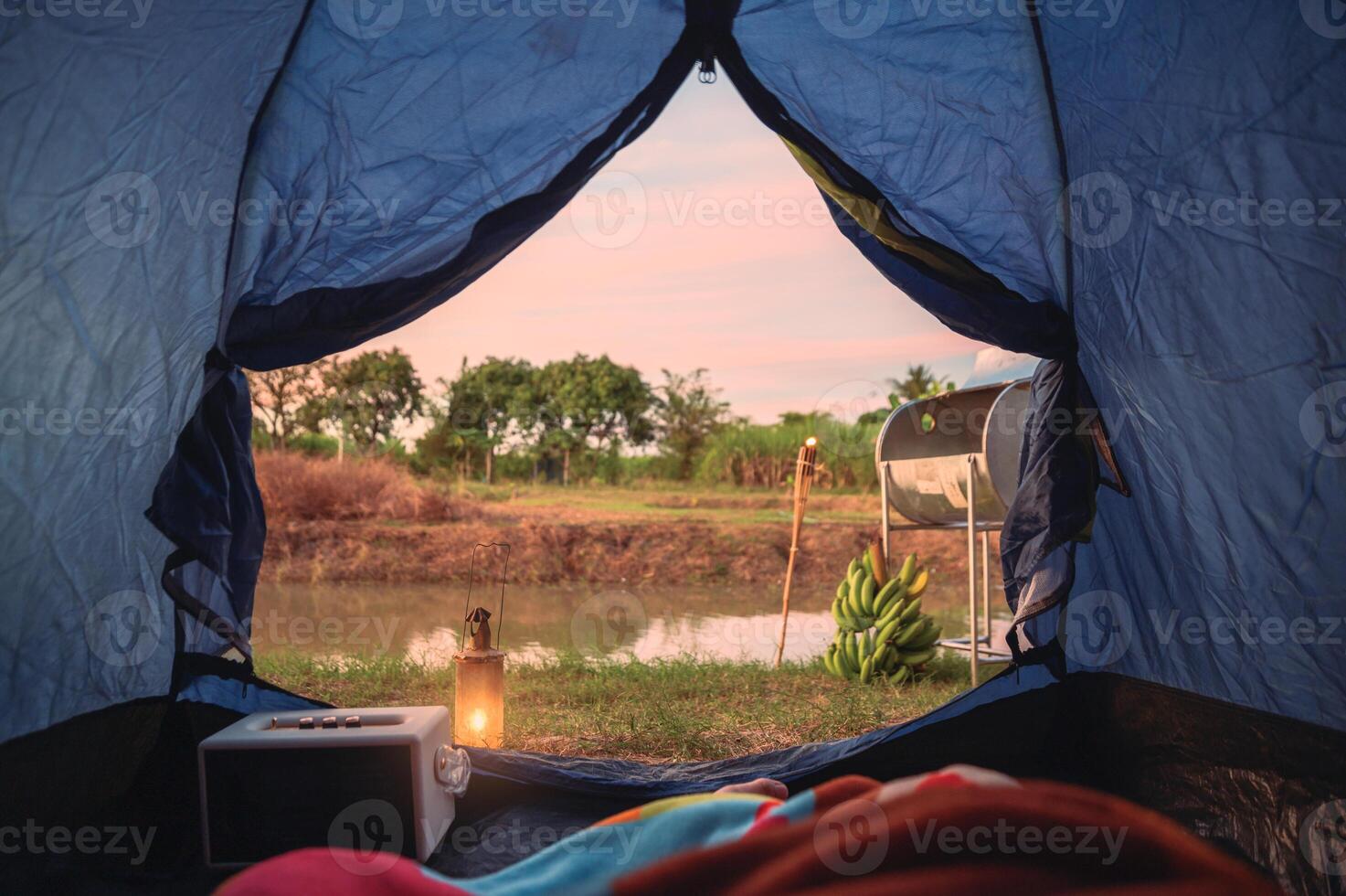 View from inside of tent with relaxing and campfire near swamp photo