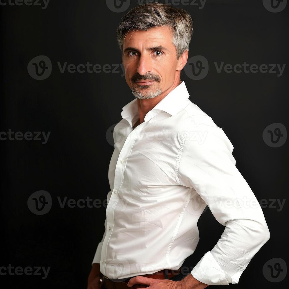 Confident Mature Man in White Shirt Posing Against Dark Background photo