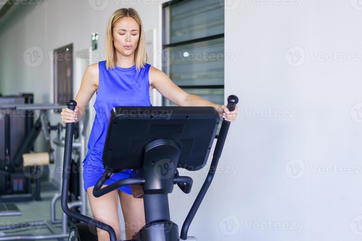 Caucasian woman on elliptical trainer at gym photo