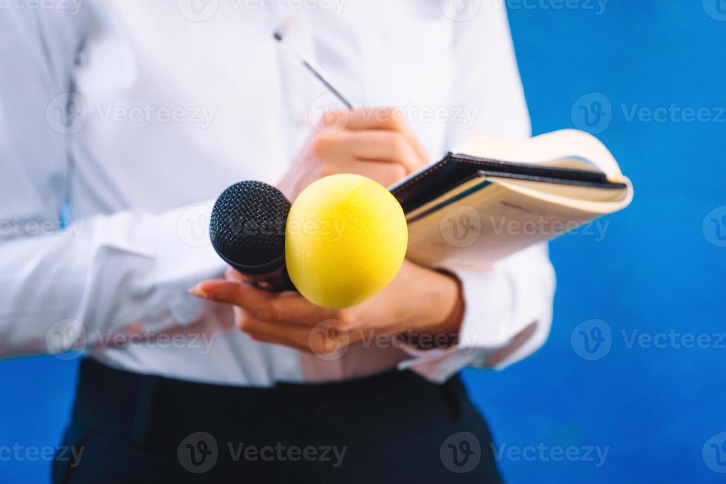 unrecognizable female reporter with a notebook, a pen and two microphones asking questions. news and report concept. photo