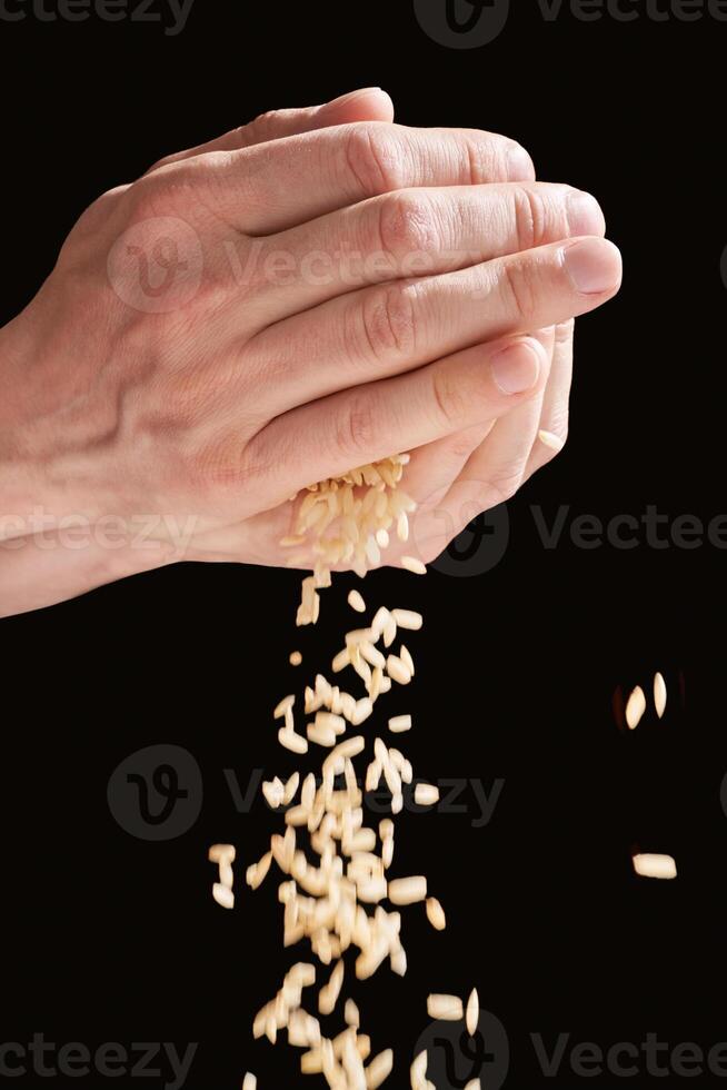 A hands hold a pile of rice, symbolizing charity, love, and hope. With cultural significance. Global effort to feed and give hope to the poor, fighting hunger and poverty. Black background photo