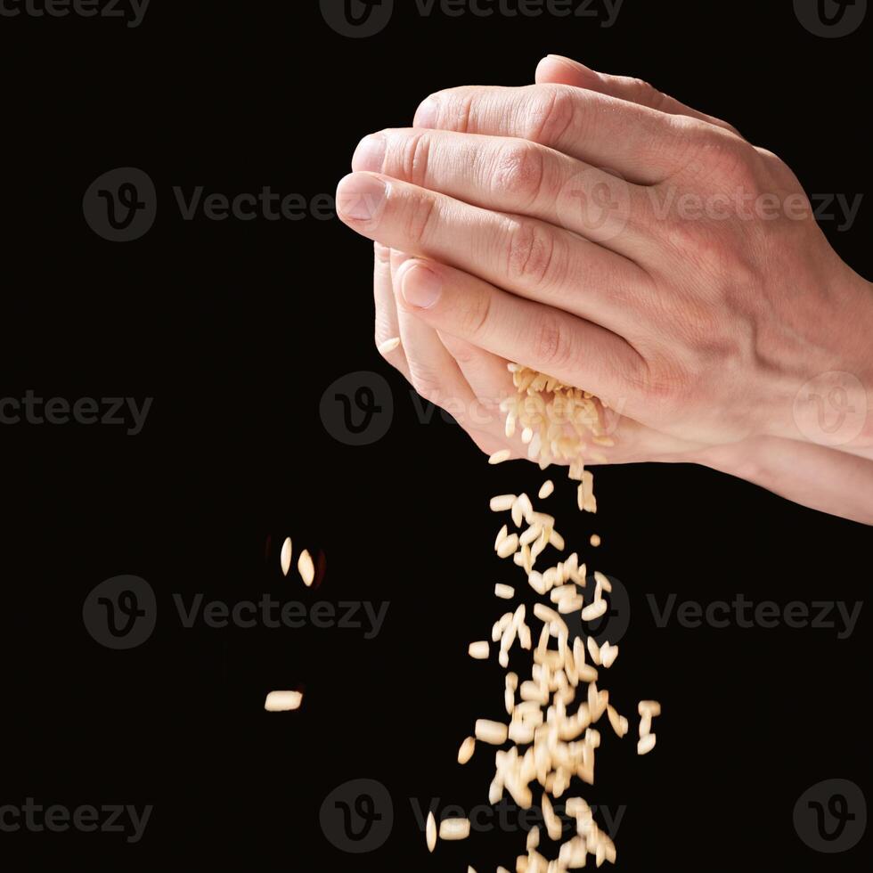 A hands hold a pile of rice, symbolizing charity, love, and hope. With cultural significance. Global effort to feed and give hope to the poor, fighting hunger and poverty. Black background photo