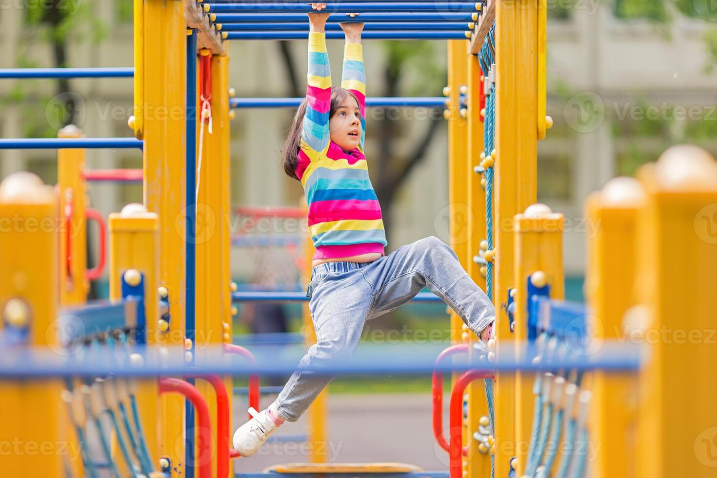 a little girl hangs on a childrens ladder on a bright playground in the park in summer photo