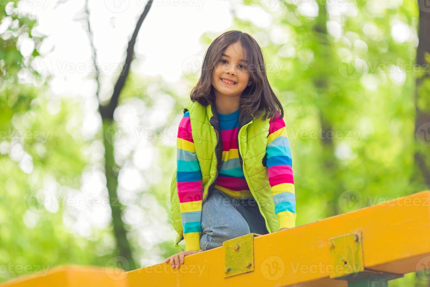Portrait of a cute little girl on a bright wooden platform in the park in spring photo