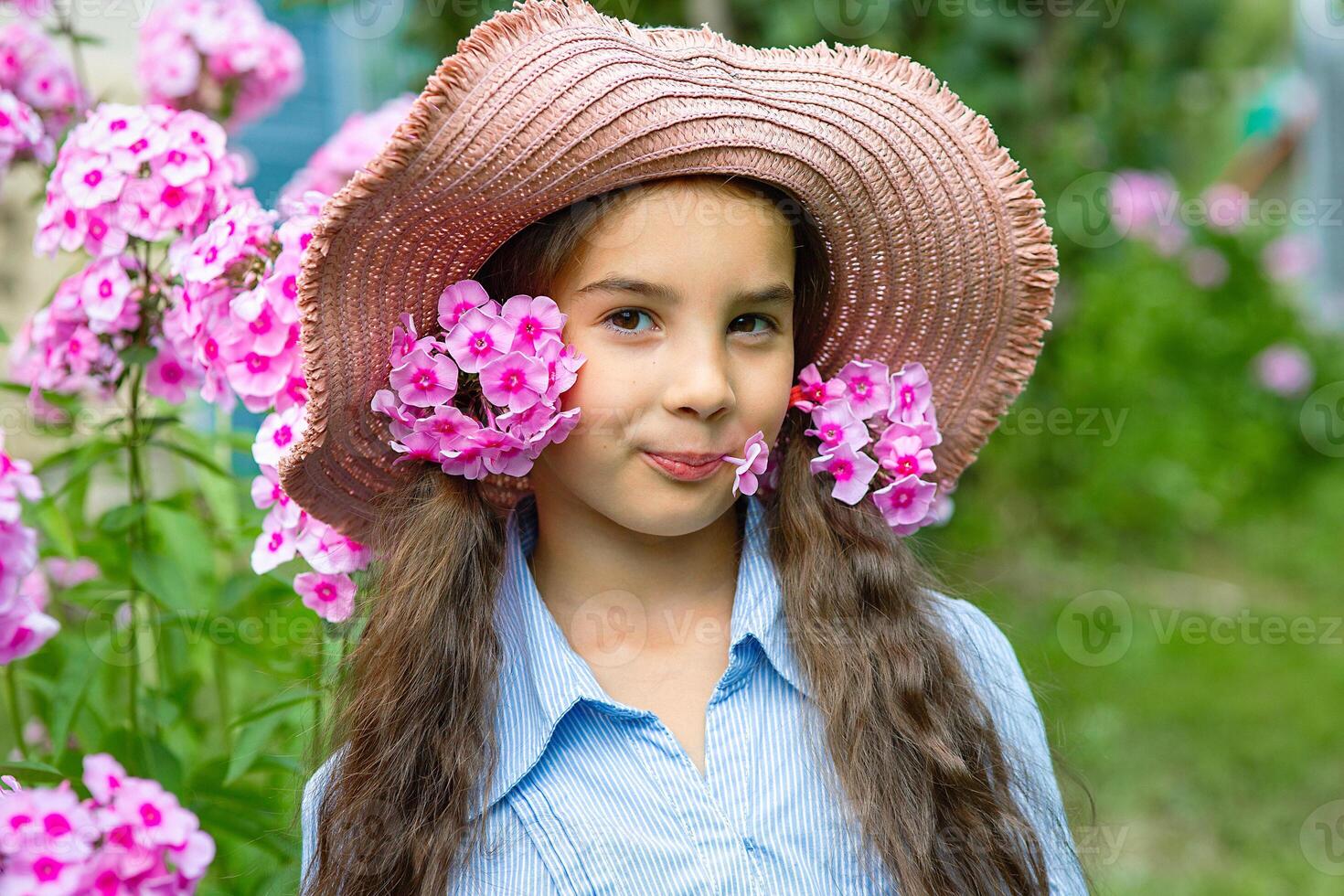 cute little girl in hat with pink flowers phlox photo