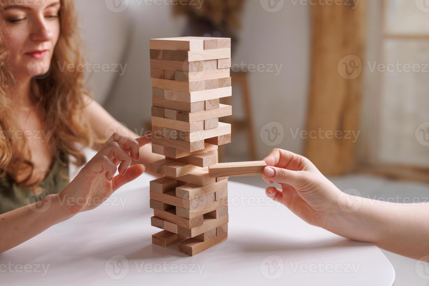 two women playing a board game made of wooden blocks at home, excitement and relaxation, mind development concept, hand motor skills, photo