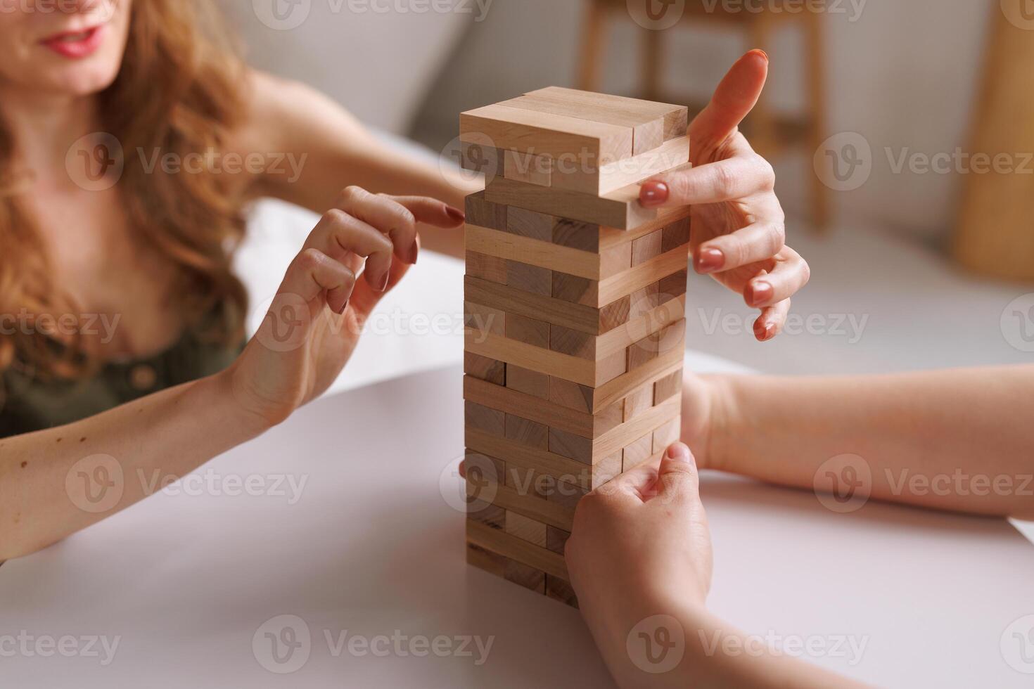 two women playing a board game made of wooden blocks at home, excitement and relaxation, mind development concept, hand motor skills, photo