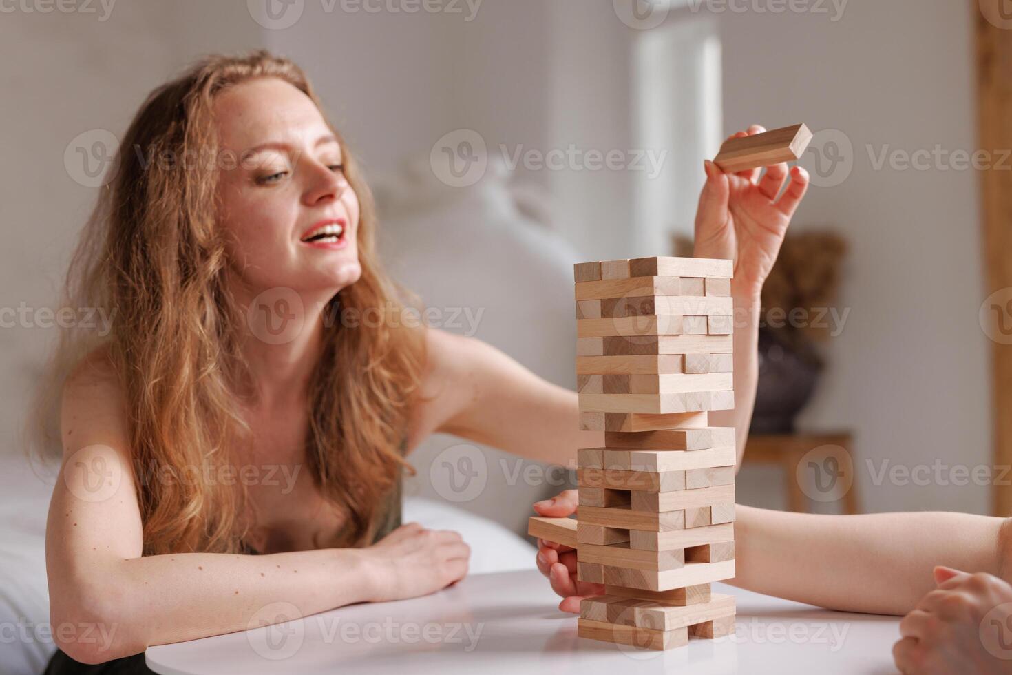 two women playing a board game made of wooden blocks at home, excitement and relaxation, mind development concept, hand motor skills, photo