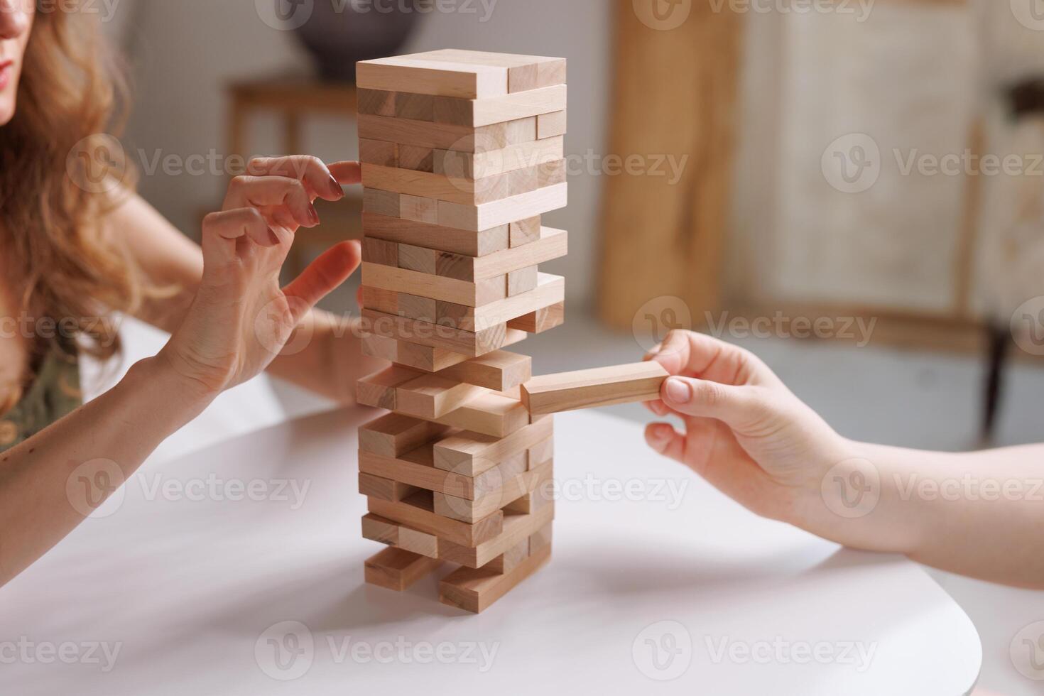 two women playing a board game made of wooden blocks at home, excitement and relaxation, mind development concept, hand motor skills, photo