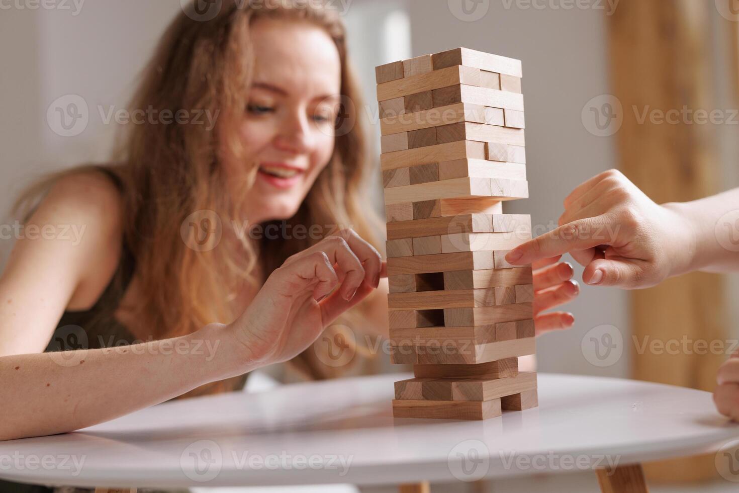 two women playing a board game made of wooden blocks at home, excitement and relaxation, mind development concept, hand motor skills, photo