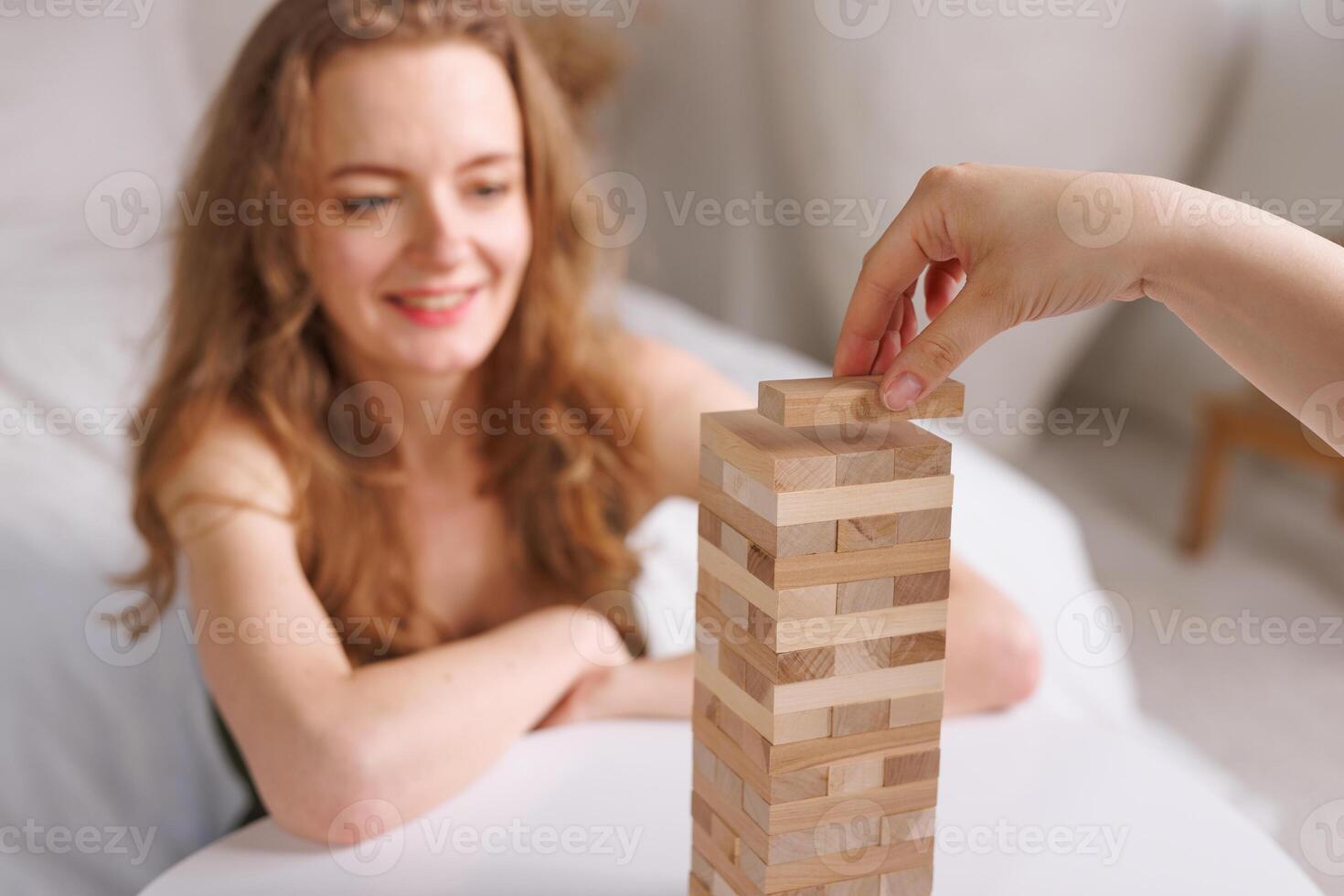 two women playing a board game made of wooden blocks at home, excitement and relaxation, mind development concept, hand motor skills, photo