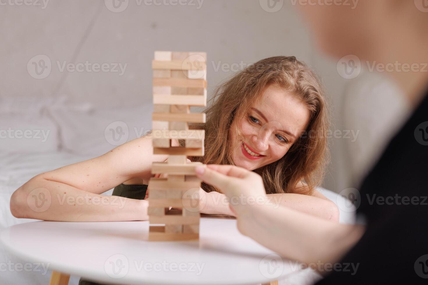 two women playing a board game made of wooden blocks at home, excitement and relaxation, mind development concept, hand motor skills, photo