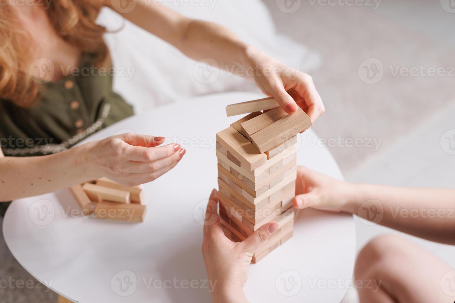 two women playing a board game made of wooden blocks at home, excitement and relaxation, mind development concept, hand motor skills, photo