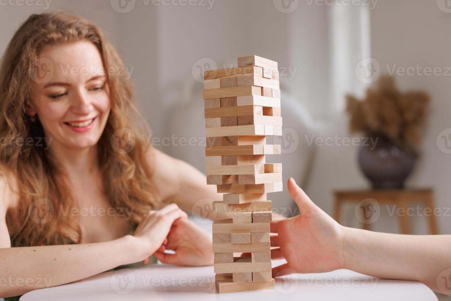 two women playing a board game made of wooden blocks at home, excitement and relaxation, mind development concept, hand motor skills, photo