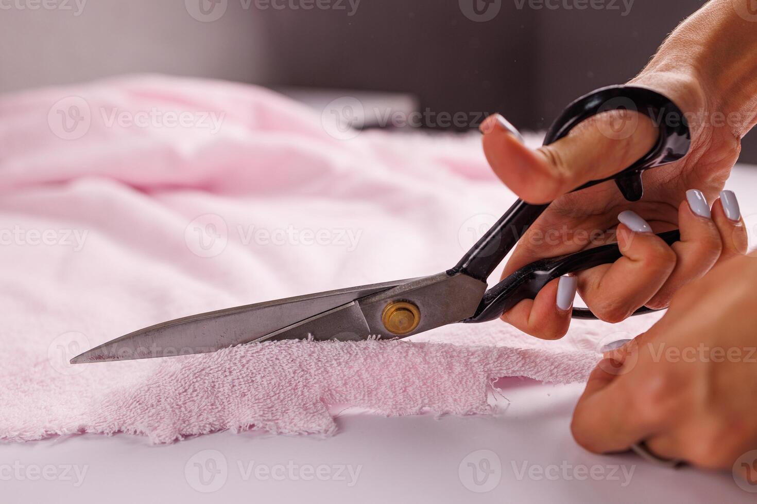 A man cuts pink fabric on a table with scissors. photo