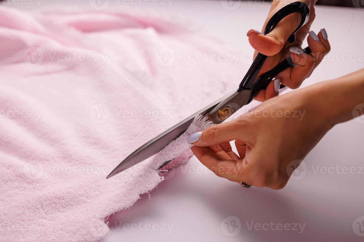 A man cuts pink fabric on a table with scissors. photo
